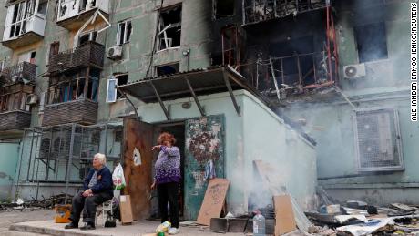 Local residents are seen outside an apartment building damaged in Mariupol on April 28, 2022. 