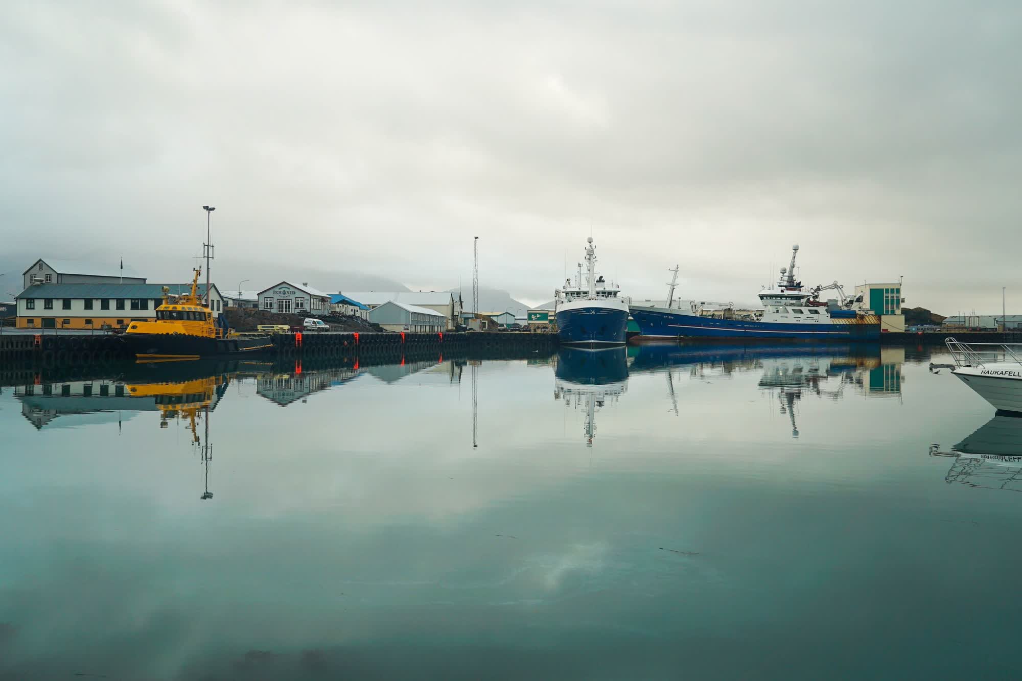 Boats dock on a still lake next to a pier.