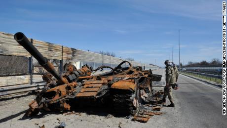 A man inspects destroyed tank of the Russian army about 40 kilometers west of Kyiv, the Ukraine capital. 