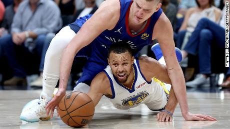 Nikola Jokic fights for a loose ball against Curry.