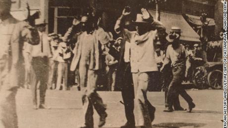 This photograph shows men walking with their hands raised during the Tulsa race massacre on June 1, 1921.