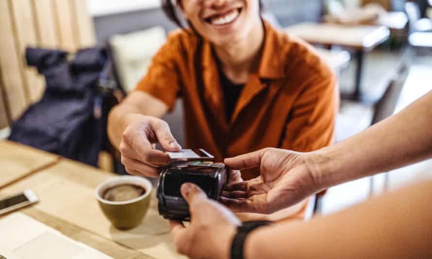 Young asian man paying by credit card in a coffee shop