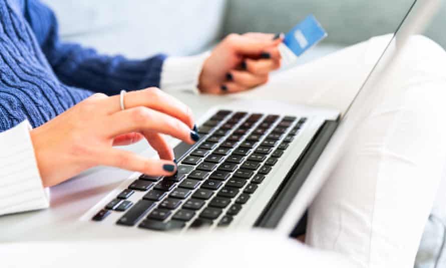 Young woman holding credit card and using laptop computer.