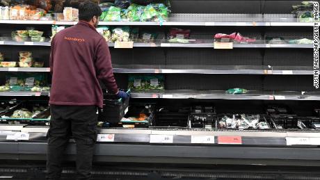 A worker restocks empty shelves of lettuce and salad leaves inside a Sainsbury&#39;s supermarket in London on September 7, 2021. 