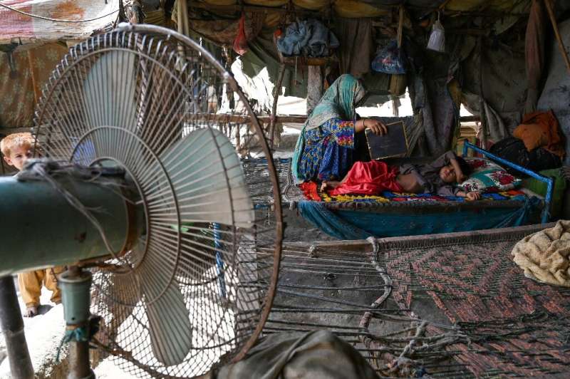 A woman uses a paper sheet to fan her child in a power cut