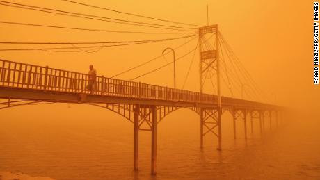 A man walks amidst a heavy dust storm along a pedestrian bridge over the Euphrates river in Nasiriyah, Iraq on May 16. Strong winds called Shamal that blow from the country&#39;s northwest commonly cause summertime dust storms in Iraq. A recent increase in storms has however turned skies orange and reduced air quality, hospitalizing some. The director of Iraq&#39;s meteorological office noted that drought is causing increased dust storms in Iraq, said NASA. 