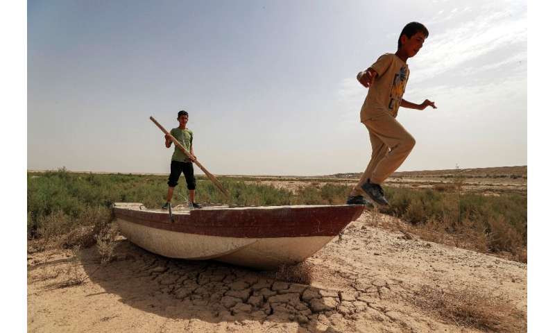 Iraqi children play on a boat grounded by the shrinking of Lake Hamrin -- the reservoir once provided fish for the dinner table 