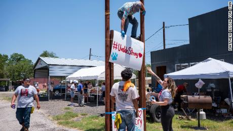 Tyler Garcia, 21, top, raises up a sign during a car wash and food sale to raise money for the families of those killed.