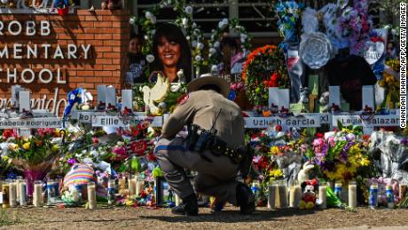 A police officer clears the makeshift memorial before the visit of President Joe Biden at Robb Elementary School in Uvalde, Texas, Sunday.