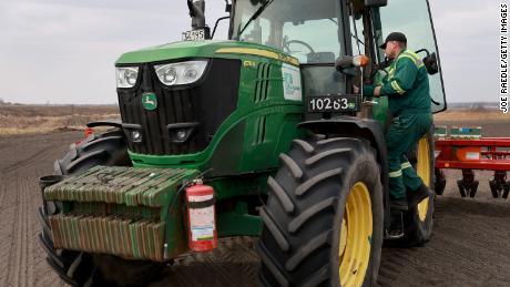 Ukrainian farmer Morda Vasyl steps into the cab of a John Deere tractor.