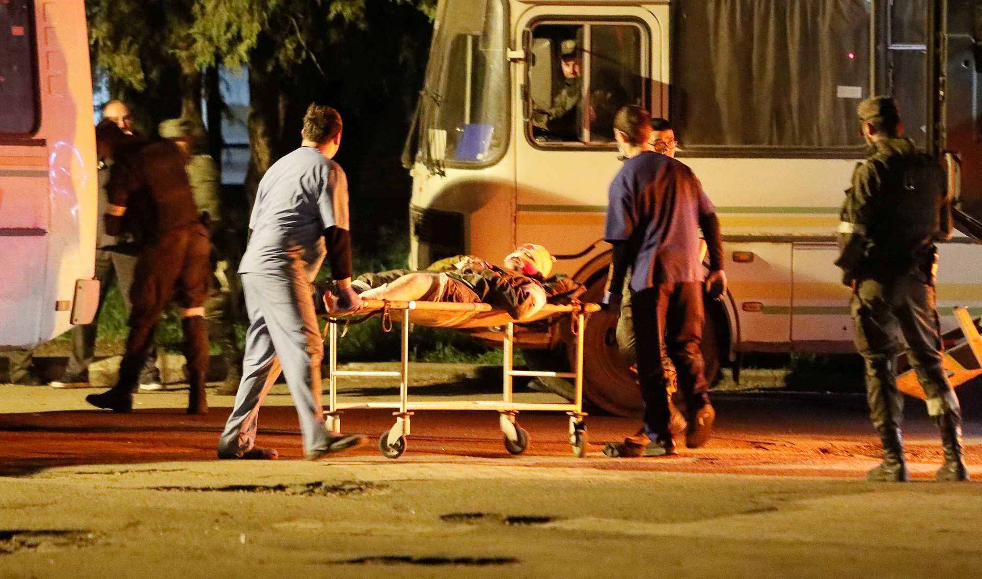 A wounded service member of Ukrainian forces from the besieged Azovstal steel mill in Mariupol is transported out of a bus on a stretcher under escort of the pro-Russian military upon arrival in Novoazovsk, Ukraine, on May 16.