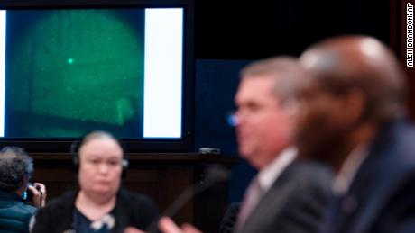 Under Secretary of Defense for Intelligence and Security Ronald Moultrie, right, and Deputy Director of Naval Intelligence Scott Bray speak with a UAP on a screen.