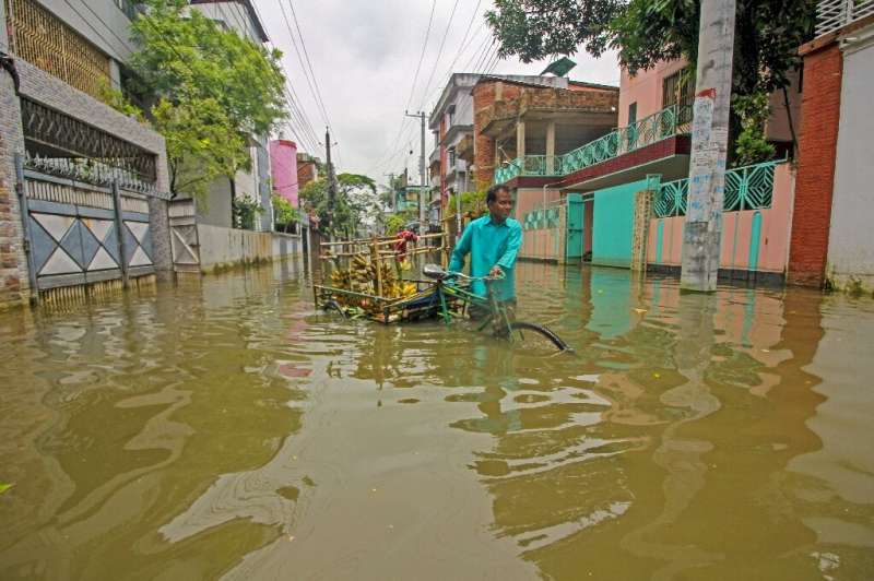 A fruit vendor sells bananas along a flooded street following heavy rains in Sylhet, Bangladesh