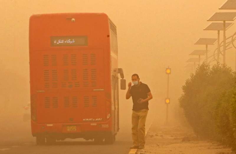 A commuter in Kuwait City waits to cross a street amid heavy sandstorms that have engulfed the Middle East