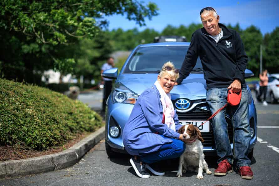 Denise and Steve Walsh with dog Lottie by their blue Toyota hybrid car.