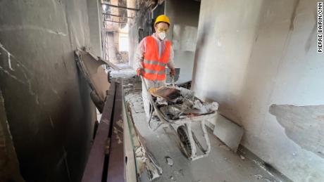 A volunteer clears debris from the damaged apartment block.