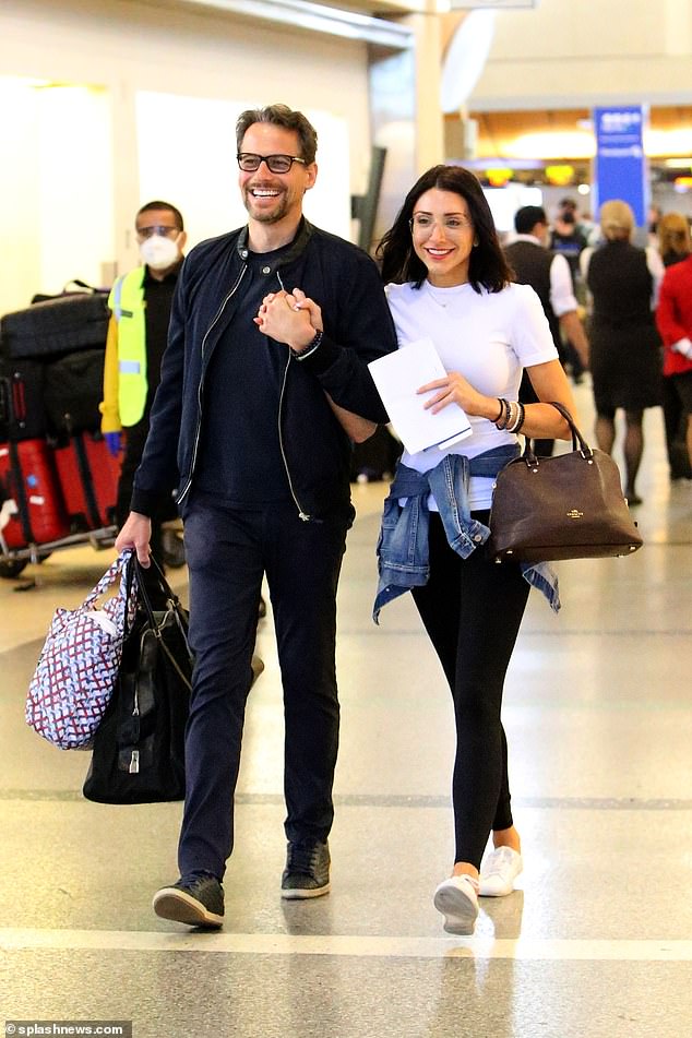 Cute: Strolling through the airport hand-in-hand with his new partner, the happy couple were all smiles as they joked about with one another