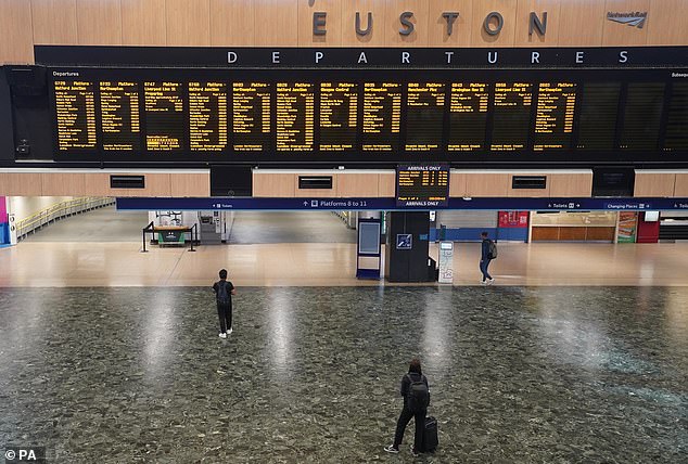 Passengers at a deserted Euston station in London this morning