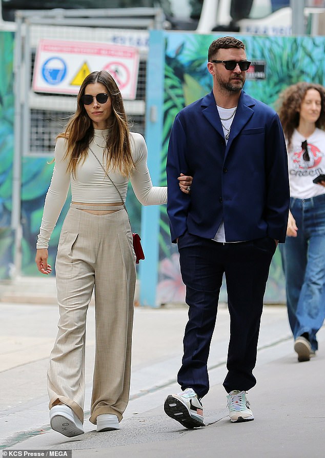 Earth tones: Jessica highlighted her fit figure in a cream-colored crop top with baggy beige pants, white platform sneakers and a crimson handbag