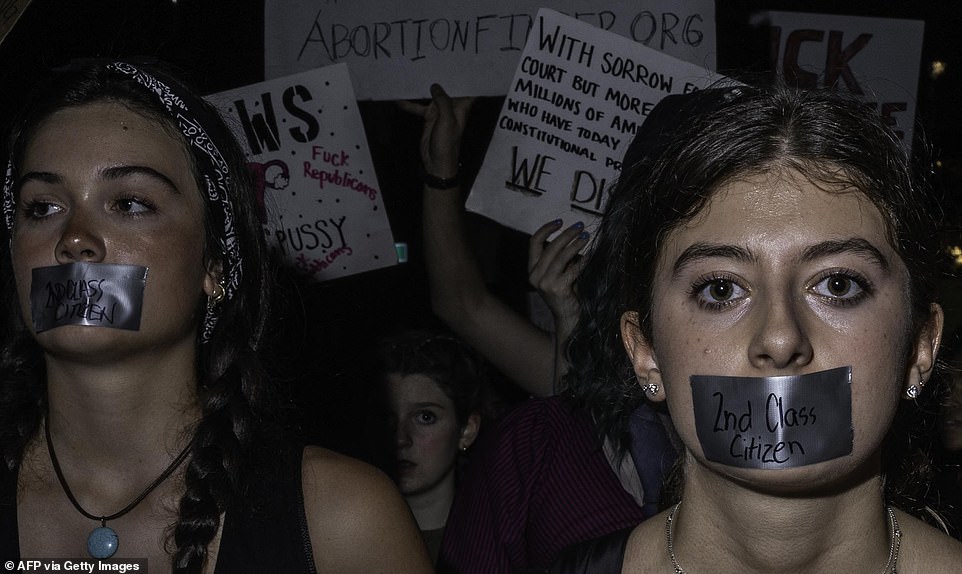 Abortion rights activists wear tape on their mouth with the words "Second Class Citizen" while protesting