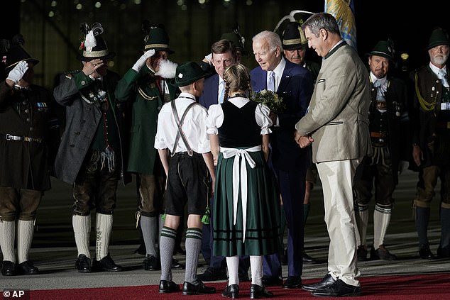 Bavarian Prime Minister Markus Soeder, right, and President Joe Biden talk with children Daniela Hauser and Marco Keller after they gave Biden a bouquet of flowers upon his arrival in Germany for the G7 meeting