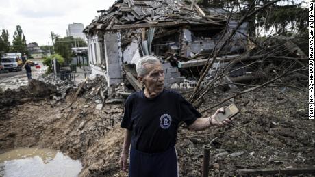 A man inspects a bomb crater after Russian artillery shells hit a district of Kharkiv on June 26, 2022.