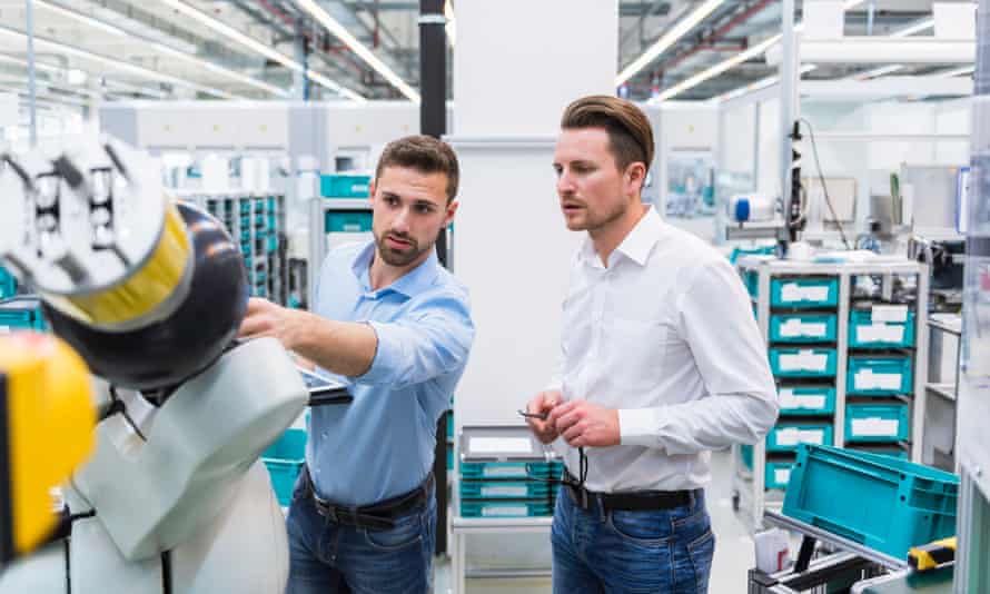 Two men with tablet examining assembly robot in factory shop floor