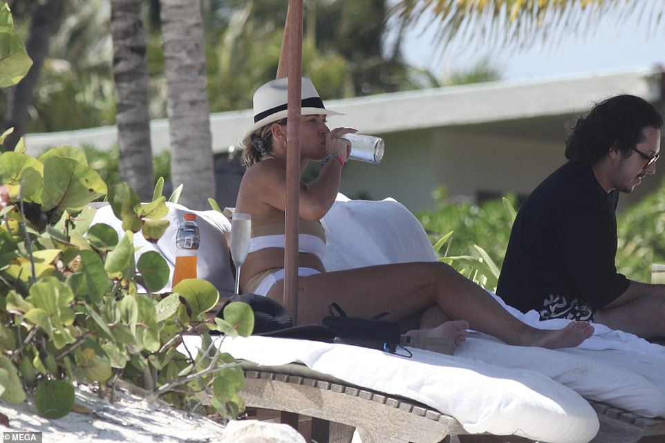 Sipping champagne: Later she took off her hat as she went for a dip and to take some pictures for her more than one million Instagram followers