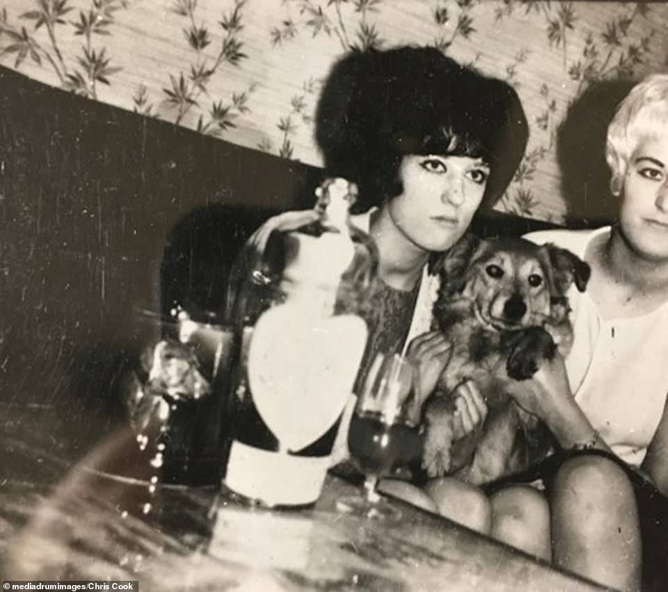 Hindley is seen right seated at a table with her sister and a pet dog. The Moors Murders took place between July 1963 and October 1965