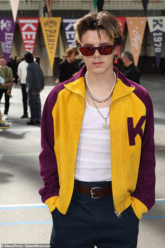 Cruz Beckham, 17, sports a gold cannabis necklace with a purple and yellow jacket at Kenzo show