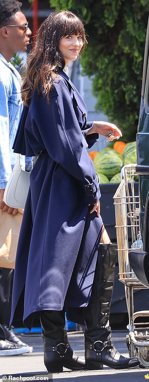 Dakota Johnson looks gorgeous in a navy blue trench coat before slipping into a slinky black skirt