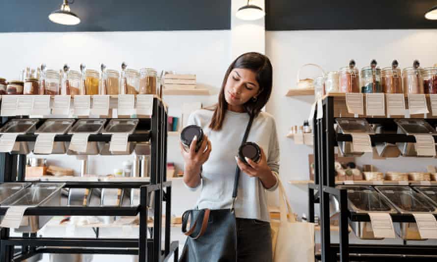 A young latin woman standing and holding two jars in a zero waste store.