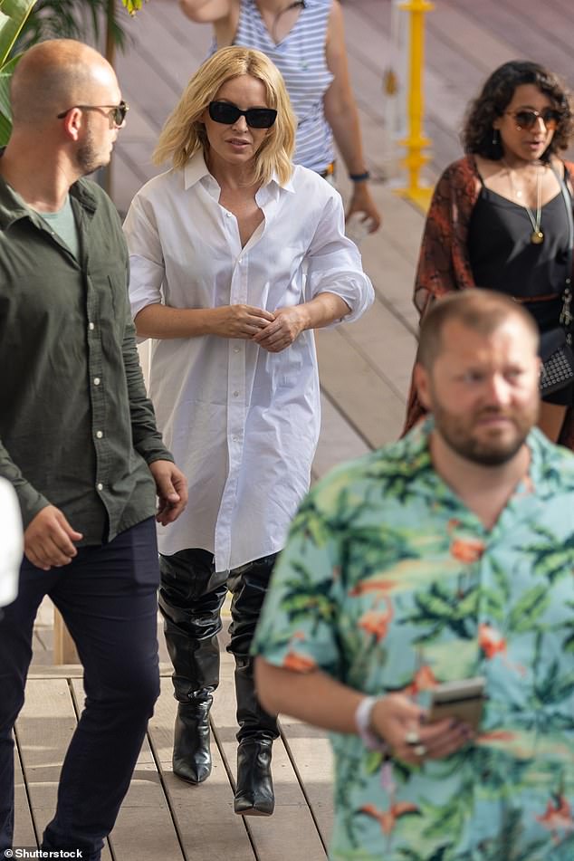 Kylie Minogue cuts a chic figure in a shirt dress and thigh-high boots