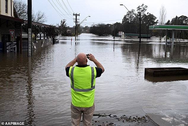 The Bureau of Meteorology's Jane Golding said the weather system delivering this downpour would be 'at it's worst' on Sunday night (pictured, residents in flood-ravaged Camden)