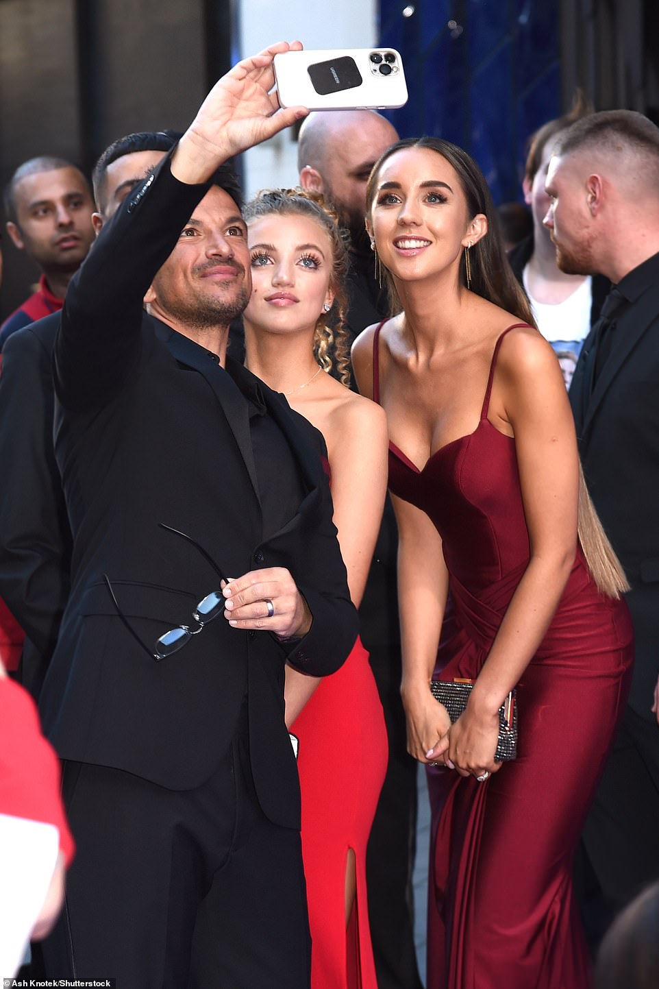 Say cheese! The singer was seen posing for a selfie with his wife, who stunned in a plunging scarlet red gown as they walked the blue carpet ahead of the charity event in London