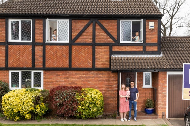 The Capes family at their old house, with the parents and youngest child outside the front door, and the other two children seen in upstairs windows