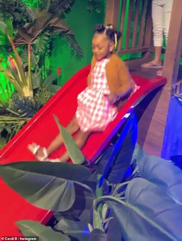 There she goes: Cardi's daughter subsequently made her way across a wooden bridge that was installed over a candy crocodile and smiled as she rode down a slide