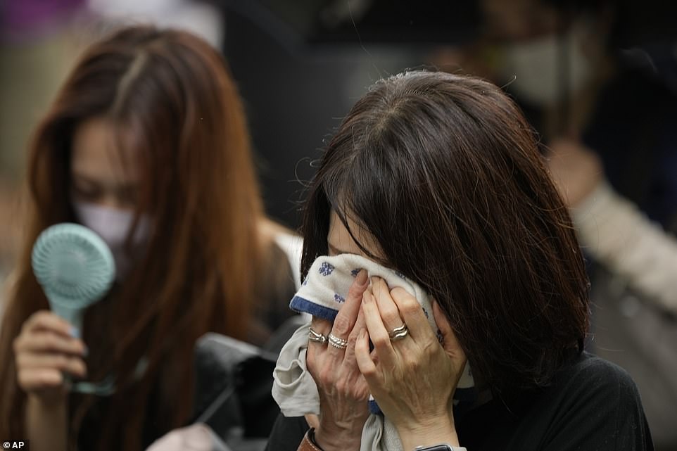 A woman buries her face in a handkerchief as she shed tears for Mr Abe, who was shot dead on Friday last week in an attack that has deeply shocked the country