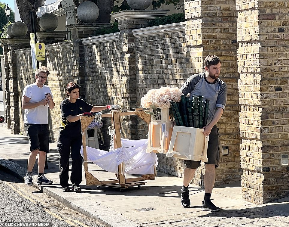 Nuptials: A team of busy workers could be seen carefully carrying props including gold picture frames through the gates along with pale pink and white floral arrangements