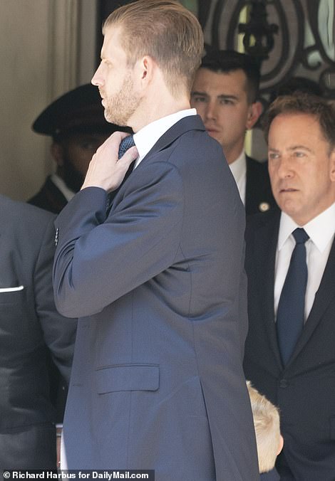 Eric Trump fixes his tie outside the funeral home