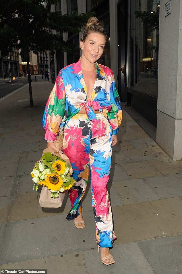 Summer vibes: Candice Brown, 37, swept her dark tresses up in a chic do as she carried a bouquet of sunflowers to the event