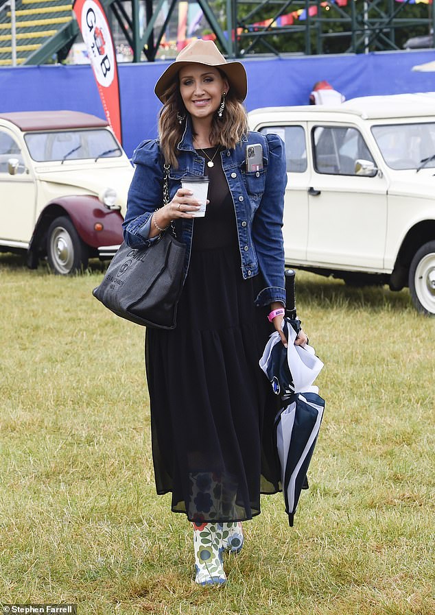 Weather prepared: While Catherine paired the piece with floral wellie boots for the festival, walking with a giant pinstripe umbrella