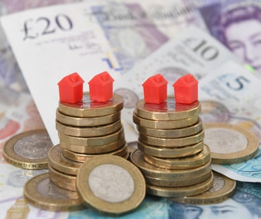 Model houses on a pile of coins and bank notes