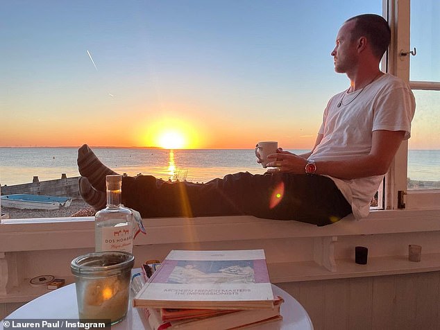 Relaxed: Another picture showed Aaron gazing out onto the beachy views as he lay back on a window ledge to watch the sunset