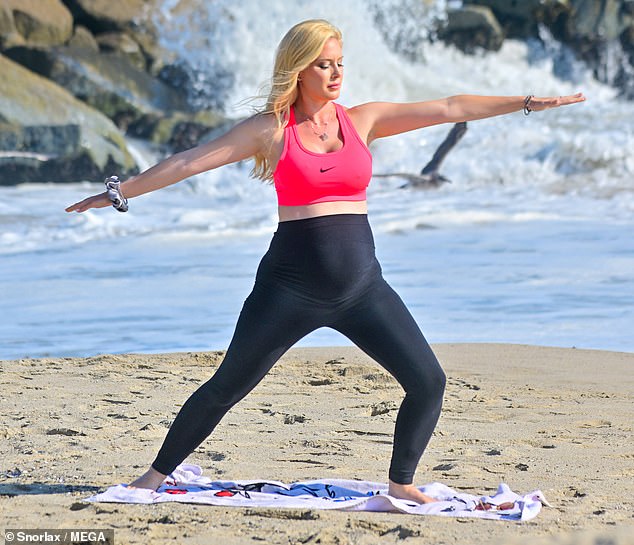 Eye-catching: She teamed her bottoms with a bright, neon pink sports bra with a black Nike swoosh logo on the front