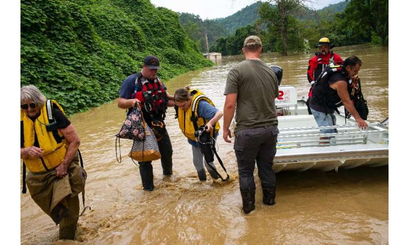 Members of a rescue team assist a family out of a boat in Quicksand, Kentucky, after flash floods