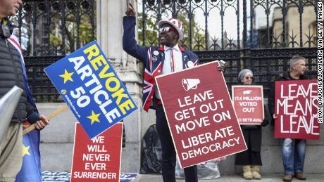 An anti-Brexit demonstrator, left, passes pro-Brexit demonstrators holding placards near the Houses of Parliament in London, in October 2019.