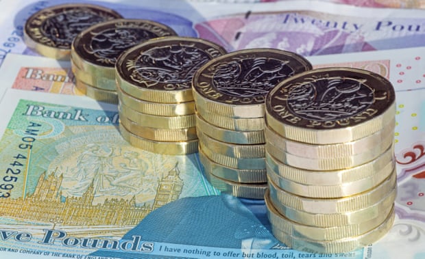 Stacks of one pound coins on British pound notes.