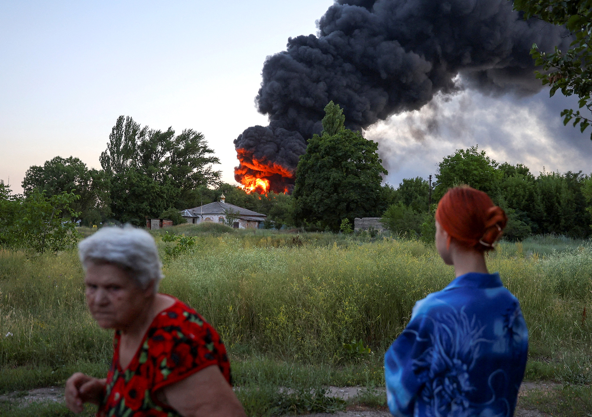 Local residents look on as smoke rises after shelling in Donetsk, Ukraine, on July 7.