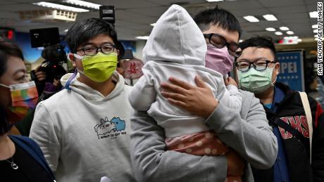 Chen Jun-ru (right, holding his daughter), and Wang Chen-wei (left) arrive at the Xinyi District Office in Taipei on January 13, 2022.